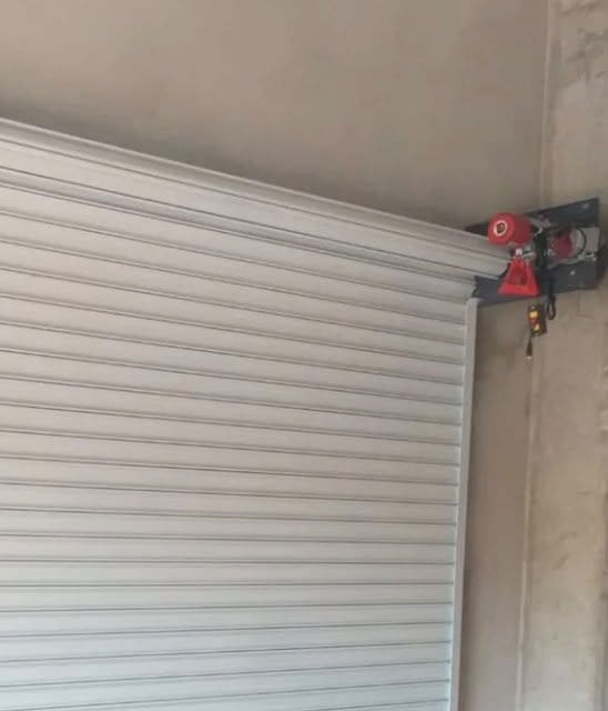 Motor de porta de enrolar instalado ao lado do rolo da porta